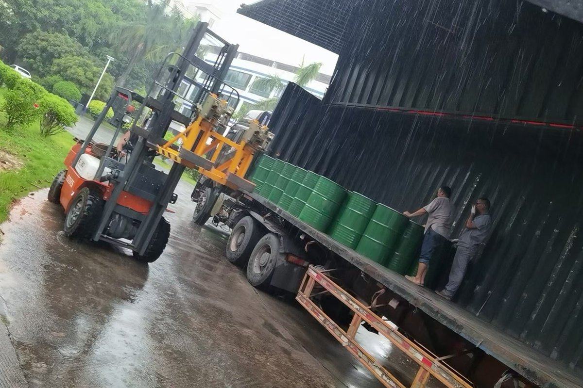 Forklift loading grease drums into a container