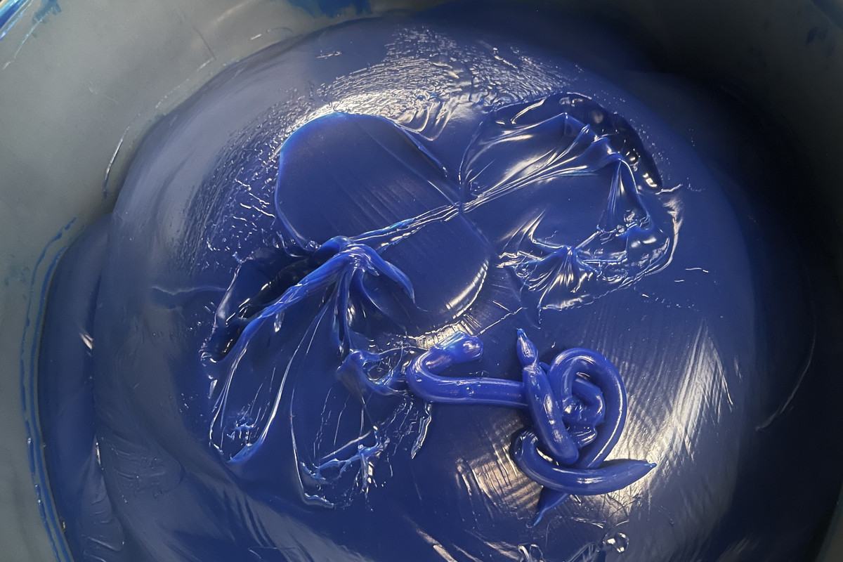 Blue high-temperature grease with smooth swirl texture in open drum